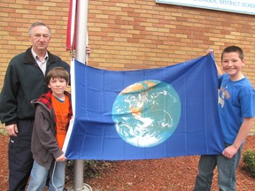 With the help of custodian Clem Vilandre, St. Ursula Catholic School students Sebastian Rupert, 9, and Patrick Buis, 12, raised a special flag to celebrate Earth Day on April 22. (Blair Andrews/Chatham This Week)