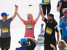 Boston Marathon bombing survivor Adrianne Haslet-Davis (C) crosses the Boston Marathon finish line with her twin older brothers Timothy (L) and David Haslet in Boston, Massachusetts, April 21, 2014. Adrianne Haslet-Davis, who lost her left leg in the bombing, joined her brothers in the last block of the marathon. REUTERS/Gretchen Ertl