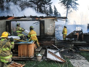 Members of Wetaskiwin Fire Services work to put out the hot spots at a fire that destroyed one home and damaged another on a rural property just south of Wetaskiwin, Alta. on April 22, 2015. Sarah O. Swenson/Wetaskiwin Times/Postmedia Network