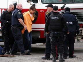 Police escort a young man into custody following a standoff at an apartment on the Lloyd Street hill in Sudbury, Ont. on Thursday April 23, 2015. John Lappa/Sudbury Star/Postmedia Network