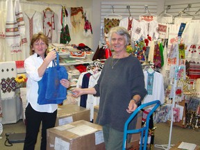 Tanya Byelik, left, and Inez Vanderhill prepare to ship handmade clothing items to Ukraine. Volunteers from Mission Circle for Ukraine ship up to four boxes overseas each month to help families in need.