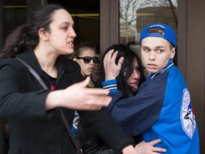 Laurie Beaudoin (2nd from right), the mother of murdered teen Connor Stevenson, is shielded as she leaves the Ottawa Courthouse on Friday April 24, 2015. 
Errol McGihon/Ottawa Sun/Postmedia Network
