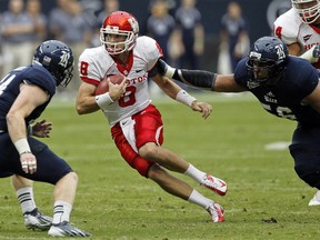 David Piland of the Houston Cougars scrambles out of the pocket against Kyle Prater and Christian Covington #56 of the Rice Owls at Reliant Stadium on September 29, 2012. (Bob Levey/Getty Images/AFP)