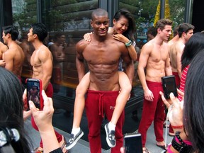 A woman poses for photographs with a shirtless model outside a department store in Singapore's Orchard Road shopping district, Dec. 14, 2011. (Reuters)