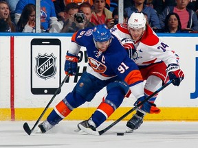 John Tavares #91 of the New York Islanders attempts to move the puck around John Carlson #74 of the Washington Capitals during the second period in Game Six of the Eastern Conference Quarterfinals during the 2015 NHL Stanley Cup Playoffs at the Nassau Veterans Memorial Coliseum on April 25, 2015 in Uniondale, New York.  Bruce Bennett/Getty Images/AFP