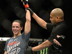 Alexis Davis (red)  has her hand raised after defeating Sarah Kaufman (blue) (not pictured) during their women's bantamweight bout during UFC 186 at Bell Centre.  Eric Bolte-USA TODAY Sports