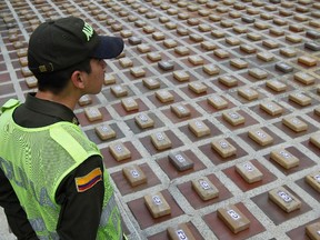 File photo of an anti-narcotics policeman guarding packs of cocaine seized in Cali January 30, 2014. The anti-drug police seized at least 650 kilos of cocaine on two semi-trailer trucks belonging to an illegal armed group called "Los Urabenos", authorities said. REUTERS/Jaime Saldarriaga