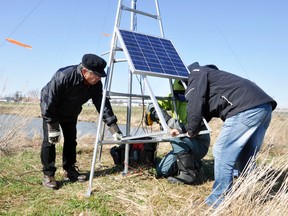 Don Jones (left), chair of the Wetlands Committee of the Energy & Environment Committee, assists Adam Timpf and David Bell of Bird Studies Canada to install the solar panel to a tower at the West Perth Wetlands that tracks migratory animals. ANDY BADER/MITCHELL ADVOCATE