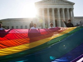 Gay marriage supporters hold a gay rights flag in front of the Supreme Court before a hearing about gay marriage in Washington April 28, 2015.   REUTERS/Joshua Roberts