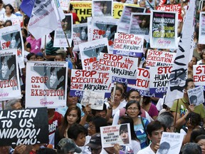 Activists display placards as they march towards Indonesian embassy, to hold a candlelight vigil for death row prisoner Mary Jane Veloso in Makati, Philippines April 28, 2015.     REUTERS/Erik De Castro