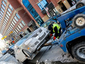 A city contract tow truck gets ready to tow a vehicle being ticketed after police found it had three or more outstanding parking tickets on King St. E. February 27, 2015. (Dave Thomas/Toronto Sun)