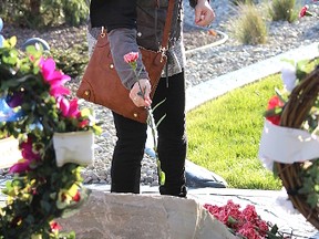 Angela Miller lays a flower in memory of her husband Jason, who died after an explosion at Veolia Environmental Services in Sarnia last fall. Miller and her children were among hundreds at Tuesday's annual Day of Mourning ceremony in Sarnia, this year at the Firefighters Memorial Gardens at the East Street fire hall. (Tyler Kula, The Observer)