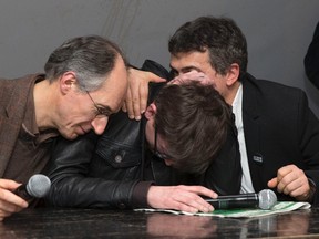 Satirical French magazine Charlie Hebdo new editor in chief Gerard Briard (L) and columnist Patrick Pelloux comfort cartoonist Luz (C) during a news conference at the French newspaper Liberation offices in Paris, January 13, 2015. Charlie Hebdo published the front page showing a caricature of the Prophet Mohammad holding a sign saying "Je suis Charlie" in its first edition since Islamist gunmen attacked the satirical newspaper.  REUTERS/Philippe Wojazer