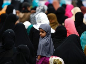 A girl looks on as Muslim women pray during morning prayers on Eid al-Fitr which marks the end of Ramadan, the holiest month in the Islamic calendar, in Colombo August 9, 2013. REUTERS/Dinuka Liyanawatte