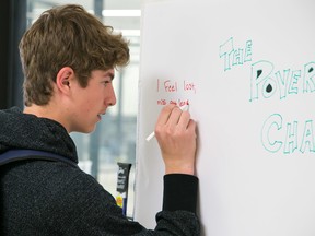 TIM MILLER/THE INTELLIGENCER
Chase Lavender, a Grade 9 student from PECI, writes on the graffiti wall at Loyalist College on Thursday as part of the Poverty Challenge Quinte. As part of the exercise students were encourages to write their frustrations on the wall as the role-play life struggling with poverty.