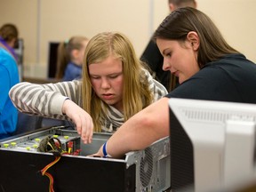 Evelyn Myall, a Grade 7 pupil from West Nissouri Public School, left, gets a helping hand from Fanshawe College electrical techniques graduate Kristine Tatare as she reassembles a computer at the Girls Rock I.T. tech conference at Fanshawe College?s School of Information Technology on Thursday. (CRAIG GLOVER, The London Free Press)