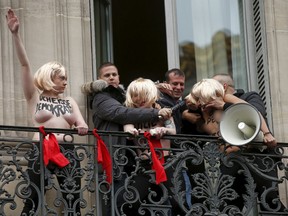 Security remove three topless activists from the Ukrainian feminist group Femen from a balcony as they give the Nazi salute to protest the gathering by France's far-right National Front political party leader Marine Le Pen (not pictured) at the party's traditional May Day tribute to Joan of Arc in Paris, France, May 1, 2015. (REUTERS/Benoit Tessier)