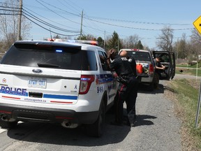 Police deal with paperwork following a high-risk takedown and temporary gun seizure Saturday afternoon south of Greely. (DOUG HEMPSTEAD/Ottawa Sun)