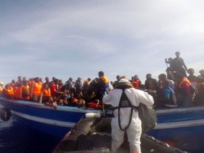 This image grab made from a handout video released by the Italian Coast Guard (Guardia Costiera) on May 3, 2015, shows an Italian coast guard taking part in a rescue operation of a boat carrying 397 migrants, on May 2, 2015, in the Mediterranean Sea.  (AFP PHOTO/GUARDIA COSTIERA)