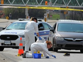 Ottawa police crime scene investigators gather evidence, including swabs from the surface of Tremblay Rd. Sunday afternoon. A young man was gunned down around 8 a.m. A pair of shoes and a pillow lay next to a car, believed to be that of the victim -- a young Somali man who is survived by his parents and seven brothers. (DOUG HEMPSTEAD/Ottawa Sun)