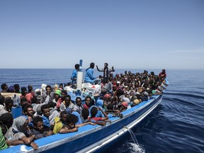 This handout picture taken on May 3, 2015 released by the MOAS (Migrant Offshore Aid Station) shows migrants aboard a wooden boat on the Mediterranean sea. Another 5,800 migrants desperate to reach Europe were rescued this weekend as they tried to cross the Mediterranean on rickety boats, more than 2,150 of them on Sunday, the Italian coastguard said.  AFP PHOTO / MOAS / JASON FLORIO