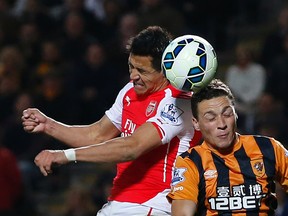 Arsenal’s Alexis Sanchez (left) and Hull City’s James Chester battle for the ball during Premier League play Monday at the Kingston Communications Stadium. (Reuters/Andrew Yates)