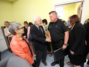 Philanthropist Maurice Rollins, centre, shakes hands with Belleville Fire Chief Mark MacDonald during the grand opening of the Maurice Rollins Centre of Hope at Canadian Mental Health Association-Hastings Prince Edward Branch in Belleville Monday.