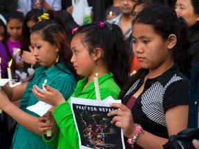 Three girls ? Anisha Gurung, 12, Ashika Gurung, 12 and Heera Gurung, 13 ? stand quietly with their candles during a Nepal vigil held at the Covent Garden Market on Monday. More than 75 people gathered to pray for the survivors of the massive earthquake that has killed more than 7,300 people. (MIKE HENSEN, The London Free Press)