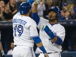 Jose Bautista (left) and Edwin Encarnacion of the Blue Jays celebrate as the Blue Jays score the go-ahead runs against the New York Yankees on May 4, 2015. (CRAIG ROBERTSON/Toronto Sun)