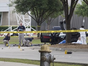 FBI and police investigators search the area around a car that was used the previous night by two gunmen, whose bodies lie covered by a tarpaulin, at the site of an exhibition in Garland, Texas May 4, 2015. Texas police shot dead two gunmen who opened fire on Sunday outside an exhibit of caricatures of the Prophet Mohammad that was organized by a group described as anti-Islamic and billed as a free-speech event. REUTERS/Laura Buckman