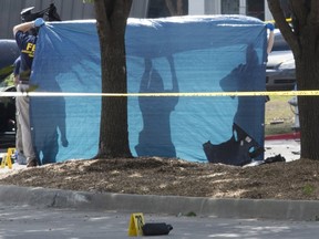 A tarpaulin is held up as the bodies of two gunmen are removed from behind a car during an investigation by the FBI and local police in Garland, Texas May 4, 2015. Texas police shot dead two gunmen who opened fire on Sunday outside an exhibit of caricatures of the Prophet Mohammad that was organized by a group described as anti-Islamic and billed as a free-speech event. REUTERS/Laura Buckman