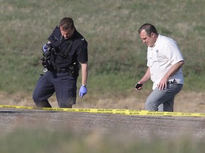 RCMP and members of the Calgary city police homicide unit investigate the scene where a body was found in a ditch at the intersection of Range Road 285 and Township Road 264 NE of Balzac on Monday May 4.