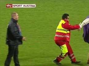 Soccer mascot "Super Leo" is helped by security as he stumbles in a drunken state. (Sky Sport Austria/screen grab)