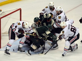 Blackhawk players swarm to protect their goal during Game 3 against the Wild on Tuesday night. (USA Today Sports)