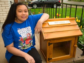 Nirakone Phromkharanourak displays a book exchange box for use in the Glen Cairn area in London. (MIKE HENSEN, The London Free Press)