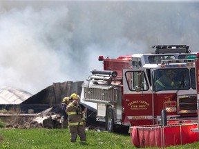 A firefighter wipes his brow while battling a fire Wednesday at 6097 Cobble Hills Rd. near Thorndale that destroyed the Smith family barn. (DEREK RUTTAN, The London Free Press)