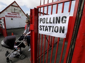 A woman pushes a buggy as she leaves a polling station at Ramsgate Football Club in Ramsgate, southeast England, May 7, 2015. (REUTERS/Suzanne Plunkett)