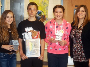 Christ the King students, from left, Karley Sterling, Ethan Houle and Kerrigan Slaney, along with teacher Courtney Mellow, show off some of the items from their class project that raised awareness about the plight of former Sudanese child soldiers. The class raised close to $1,300 in a partnership with the international charity GUA Africa.