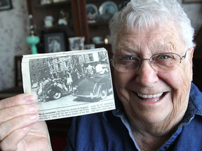 June McGlynn holds up a newspaper copy of a photo taken of her riding the running board of a car down Princess Street to celebrate VE Day on May 8, 1945. (Michael Lea/The Whig-Standard)