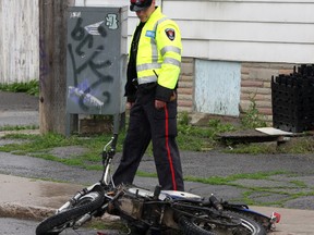 Kingston Police traffic accident re-constructionist Steve Harvey looks over a mangled motorcycle that was involved in a collision with a mini van at the corner of Patrick and John Street on Tuesday afternoon July 8 2014. The two people on the motorcycle were taken to hospital with serious injuries while two occupants of the van suffered minor injuries.  IAN MACALPINE/KINGSTON WHIG-STANDARD/QMI AGENCY