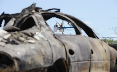 Electricity workers are seen through the window of a burned out automobile as they work at restoring power lines in a destroyed neighborhood in Slave Lake, Alberta May 17, 2011. Parts of the town were devastated by wild fires that rolled through the area late Monday night and early Tuesday morning. About 100 wildfires are burning in Alberta, spurred by warm temperatures and gusting winds, with 23 considered out of control in a fire season unlike any seen before.  REUTERS/Todd Korol
