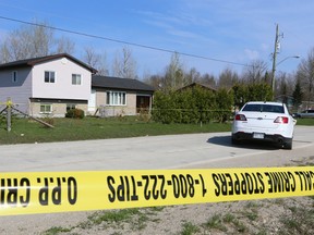 Police tape surrounds a section of Kewageshig St. and a pair of homes, between Cameron Dr. and Mason Dr., and an unmarked O.P.P. cruiser, on The Saugeen First Nation Reserve on Friday, May 8, 2015 near Southampton, Ont.  The area is the site of a murder investigation by Bruce County OPP.  James Masters/Owen Sound Sun Times/Postmedia Network