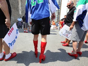 Mayor of Belleville, Ont. Taso Christopher, second from right, looks at this man's women's high heal boots before the fifth Walk a Mile in Her Shoes fundraiser event hits the road in downtown Saturday, May 9, 2015.  -  Jerome Lessard/Belleville Intelligencer/Postmedia Network