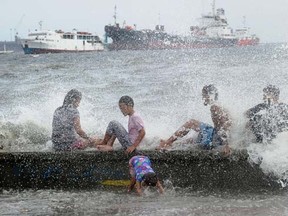 Residents along Manila Bay play in the waves created by nearby Typhoon Noul on May 10, 2015 as it approaches the northern Philippines.  AFP PHOTO / Jay DIRECTO