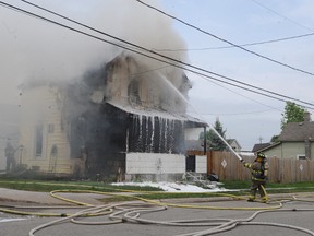 Two Brockville firefighters to the left are shrouded in smoke as a third trains a hose on the front of a Havelock Street home that was gutted by fire Monday afternoon. (Nick Gardiner/Brockville Recorder and Times)