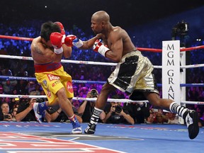 Manny Pacquiao of the Philippines covers his face as he is punched by Floyd Mayweather, Jr. of the U.S. in the first round during their welterweight WBO, WBC and WBA (Super) title fight in Las Vegas, Nevada, May 2, 2015. (REUTERS/Steve Marcus)