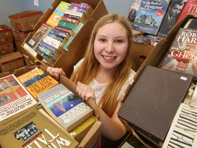 Luke Hendry/The Intelligencer
Interim fund development co-ordinator Amelia Huffman holds one of hundreds of used books waiting to be sold at the Alzheimer Society of Hastings-Prince Edward office in Belleville Tuesday. The society's next sale runs June 2 to June 4 at the Bay View Mall.