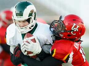 Addison Richards of the University of Regina Rams scores a touchdown despite being wrapped up by Jamahl Knowles of the University of Calgary Dinos during the Hardy Cup CIS west final at McMahon Stadium in Calgary, Alta. on Saturday, Nov. 10, 2012. The Dinos were going for their fifth straight Hardy Cup. Lyle Aspinall/Calgary Sun/QMI Agency