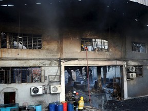 Firemen and rescuers look for the victims trapped in a fire at a factory in Valenzuela, Metro Manila in the Philippines May 13, 2015. A fire at a Philippine rubber slipper factory killed 31 workers on Wednesday and dozens were missing and feared dead, government and fire officials said.    REUTERS/Ezra Acayan