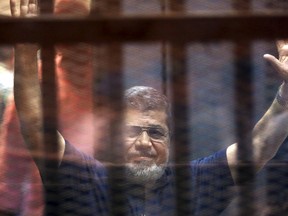 Former Egyptian President Mohamed Mursi waves as he enters for his trial with other Muslim Brotherhood members at a court in the outskirts of Cairo, May 16, 2015.  REUTERS/Mohamed Abd El Ghany